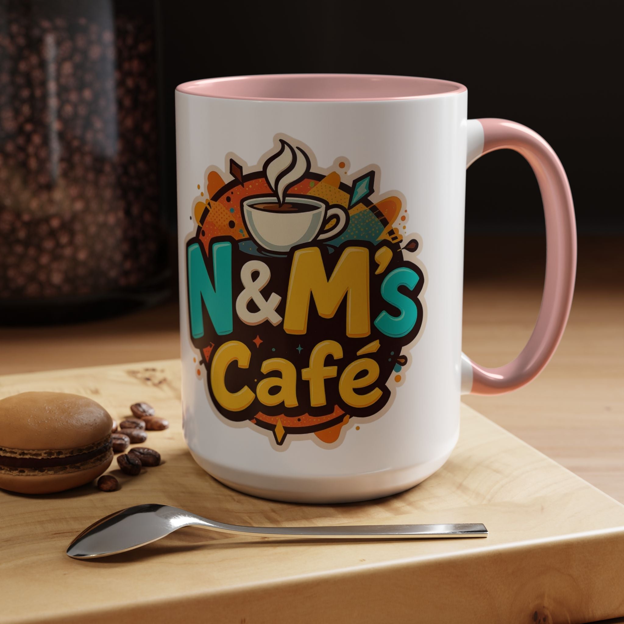 Ceramic Coffee Mug featuring the vibrant design of N&M's Café, set on a wooden table with coffee beans and a macaroon.