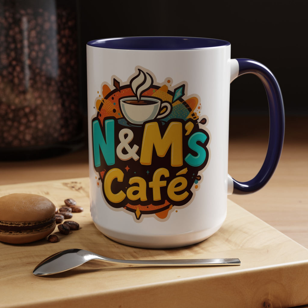 Ceramic Coffee Mug with vibrant N&M's Café branding, set on a wooden table with coffee beans and a spoon, perfect for cozy moments at home.